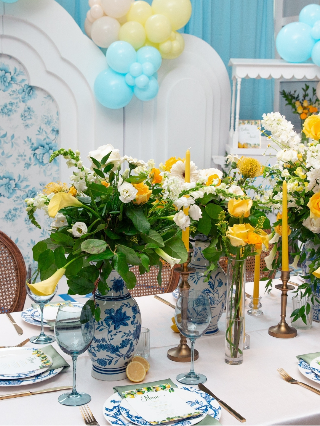 Finished luncheon tablescape with blue-and-white chinoiserie vases, yellow roses, calla lilies, and taper candles