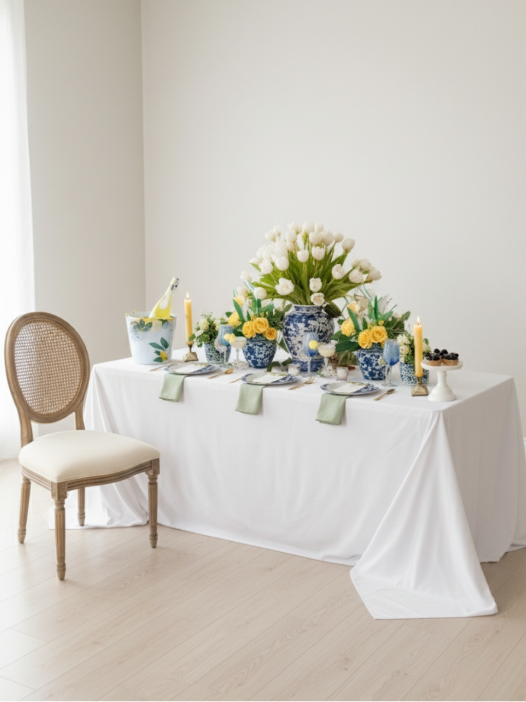 Luncheon table concept: white linen, blue-and-white vases, white tulips, and yellow roses in an empty room